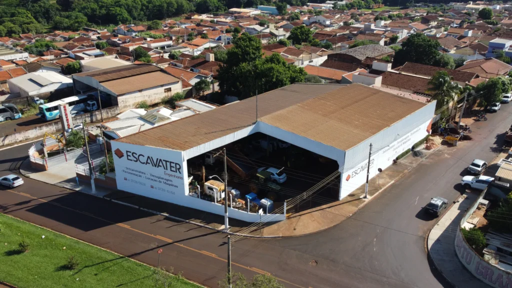 Vista aérea da sede da Escavater Engenharia, mostrando o galpão da empresa com veículos e máquinas estacionados.