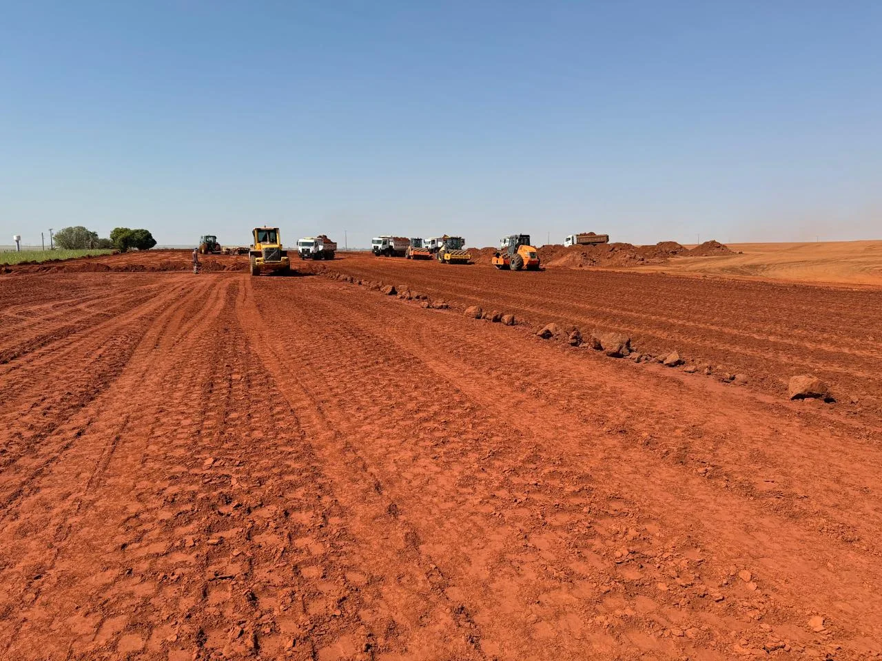 Escavadeira carregando caminhão em obra de terraplenagem da Tello Fertilizantes