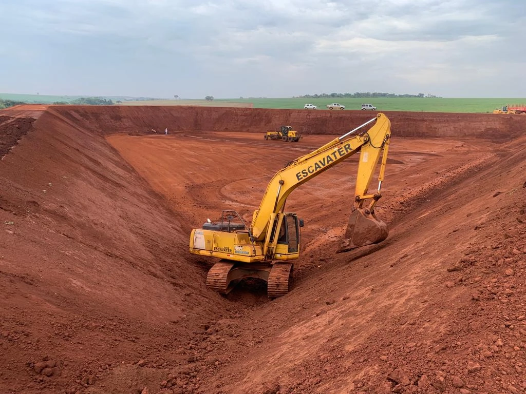 Escavadeira executando talude em tanque de vinhaça durante terraplenagem industrial
